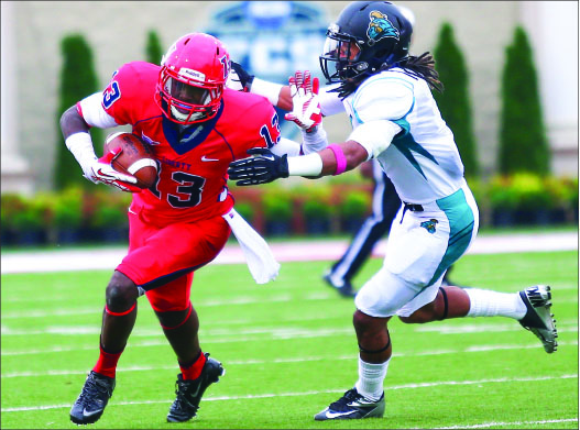 CREATING SPACE — Darrin Peterson (13) attempts to stiff-arm a defender in Liberty’s loss to No. 3 Coastal Carolina. Photo credit: Courtney Russo