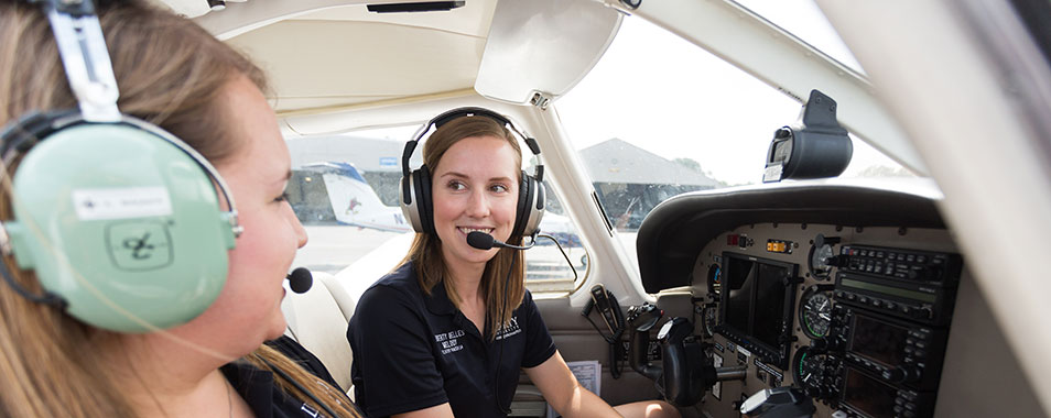 Alt="Two girls sitting in the cockpit of an airplane."