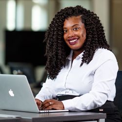 Smiling student in professional business wear working on her laptop.