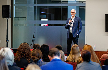 Speaker addressing a room full of people at the School of Business CEO Summit event.