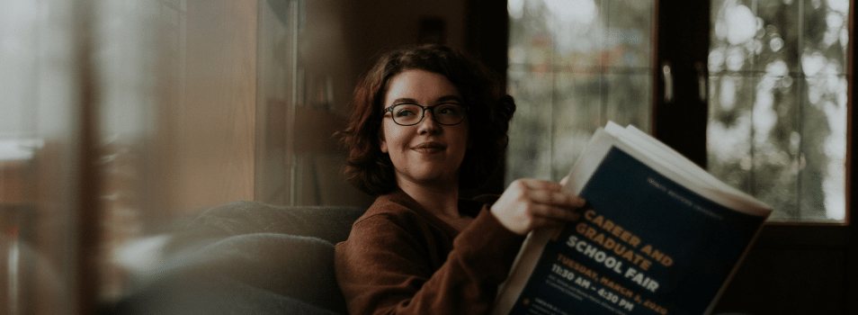 A woman sitting with a newspaper about a career fair