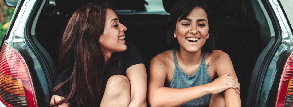 Two women sitting in a car trunk laughing