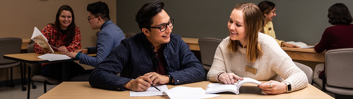 Students sit at a table doing homework together.