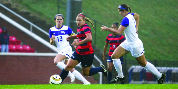 slice and dice — Sophomore midfielder Brittany Aanderud dribbles the ball between two High Point defenders Saturday afternoon. Photo credit: Courtney Russo