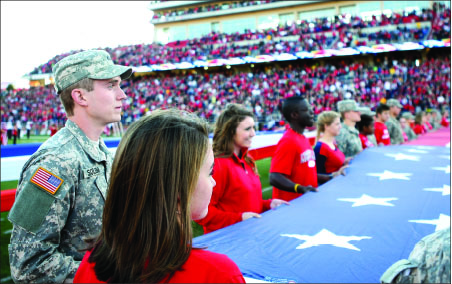 recognition — Students and soldiers display a giant American flag covering most of the field during halftime of the Liberty vs. VMI football game. Photo credit: Ruth Bibby