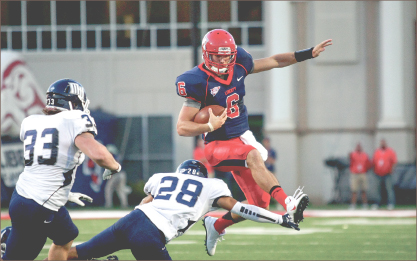 Rise Up — Quarterback Josh Woodrum hurdles over a diving Monmouth defender. Photo credit: Ruth Bibby