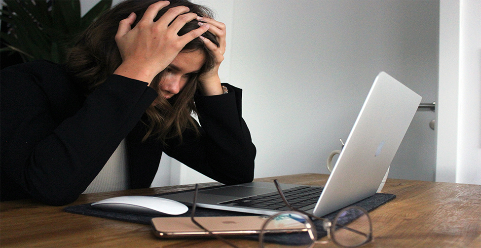 Photo of burned out student at a computer. Photo from Unsplash by SEO Galaxy.