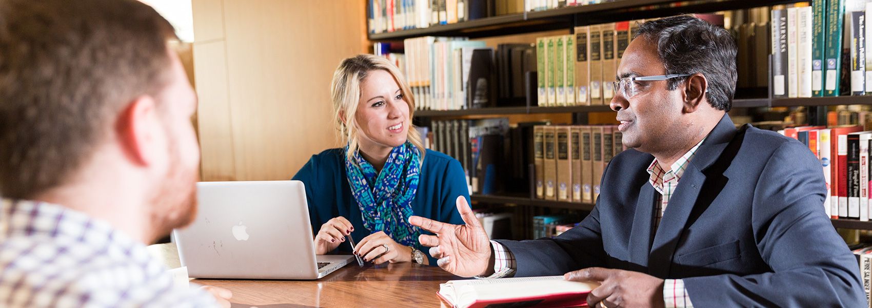 students talking with a professor in the library