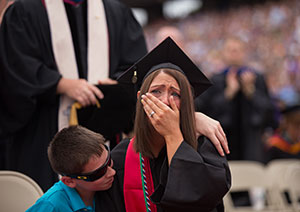 Malory Mallery reacts as her husband, Sgt. Mark Mallery, currently deployed in Afghanistan, shares his congratulations via video during the Commencement ceremony.