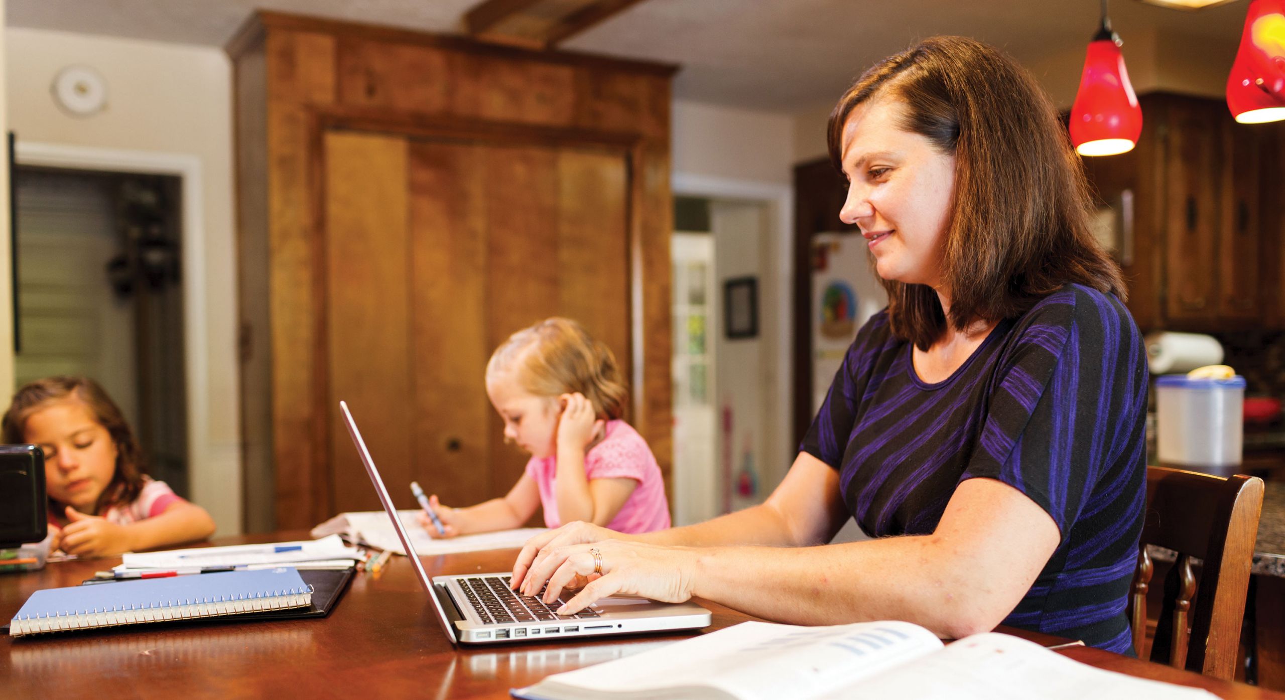 A family studies together in the kitchen.