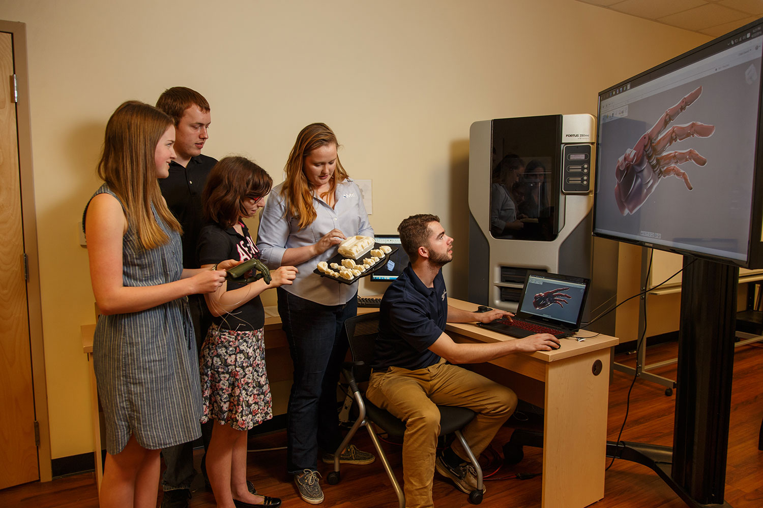 Katelyn Denyer, a rising mechanical engineering junior, Ben Schubert, a rising mechanical engineering junior, local high schooler Natalia Griffis, AMTI engineer Lindsay Davis, and Chad Calvert, a junior engineering student, work together on the mechanics and grip.