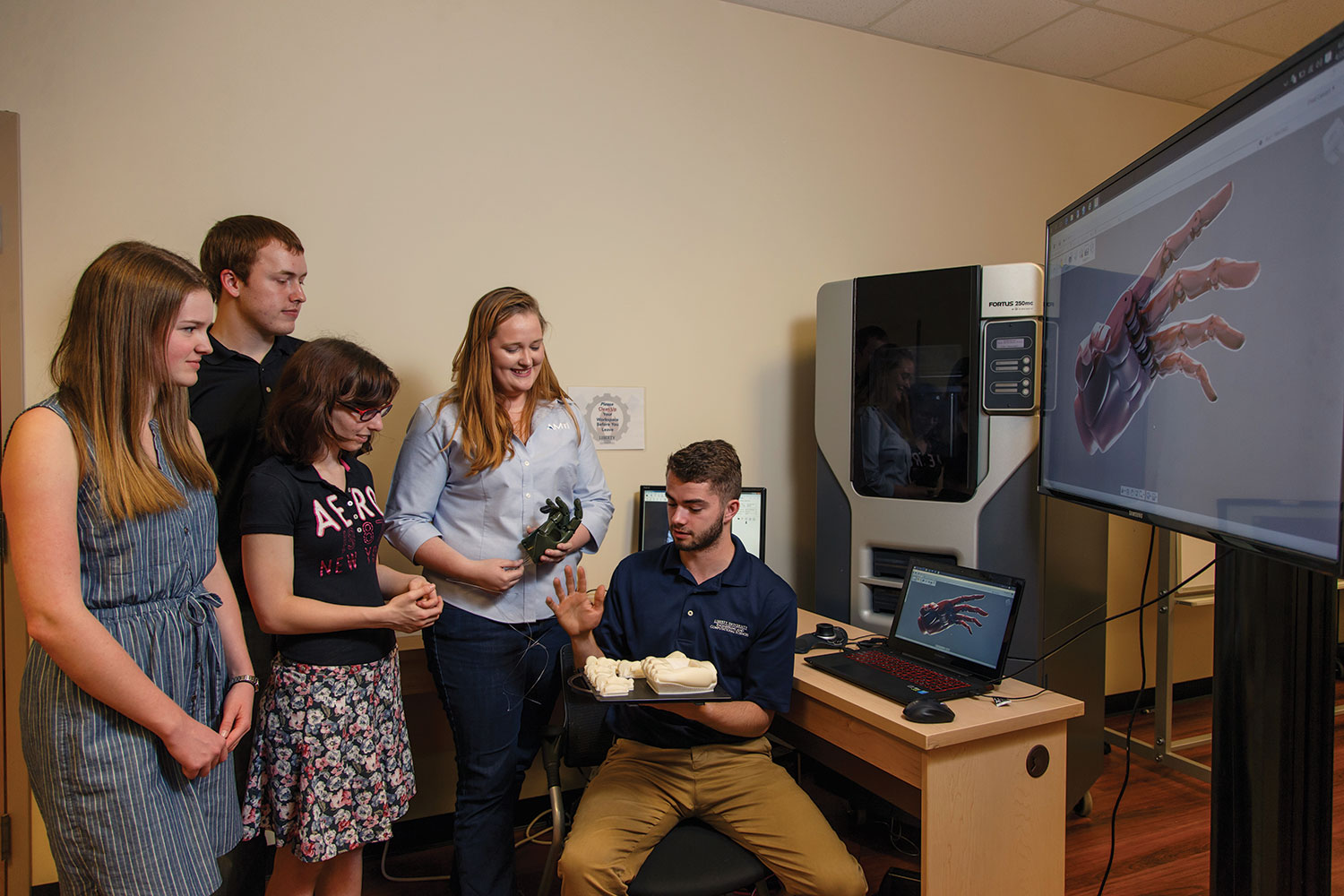 Katelyn Denyer, a rising mechanical engineering junior, Ben Schubert, a rising mechanical engineering junior, local high schooler Natalia Griffis, AMTI engineer Lindsay Davis, and Chad Calvert, a junior engineering student, work together on the mechanics and grip.