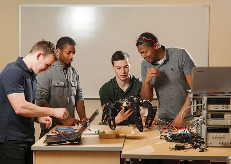 A team of engineering students work with a hexapod.