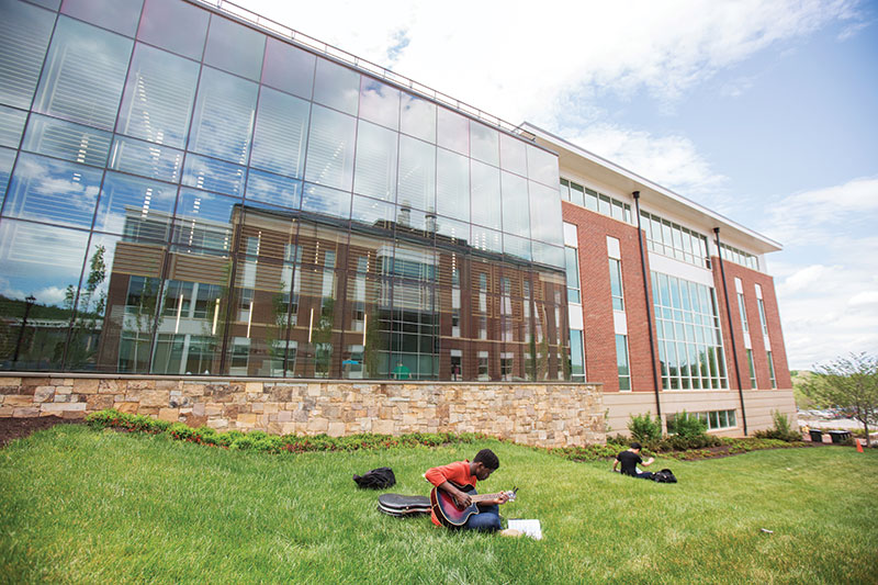 A Liberty University student plays guitar on the lawn outside of the new Center for Music and the Worship Arts.