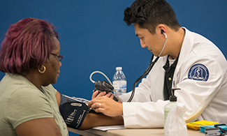 LUCOM student-doctor checks vitals of Danville outreach patient.