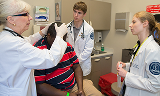 Kathy Bogacz, M.D., assesses patient with student-doctors.