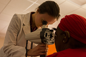 LUCOM student-doctor examines eye of patient.