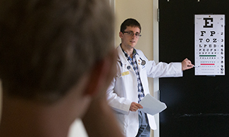 LUCOM student-doctor performs eye exam with student-athlete