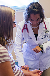 LUCOM student-doctor Mary Bhajjan checks patient's vitals.