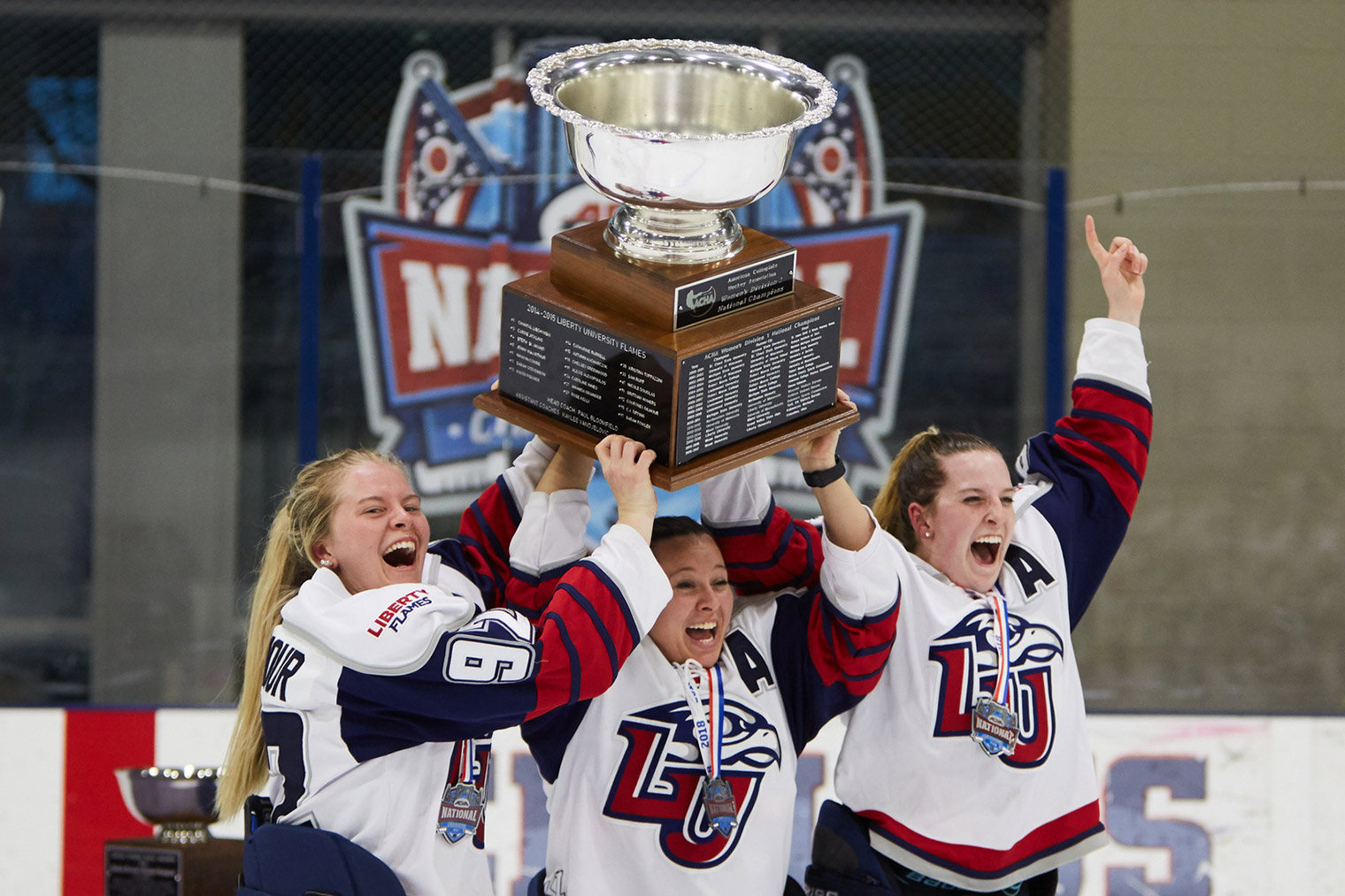 Liberty captains Courtney Gilmour (left), C.J. Tipping, and Vanessa DeMerchant raise the ACHA Division I women's hockey championship cup in Columbus, Ohio. (Photo by Joel Coleman)