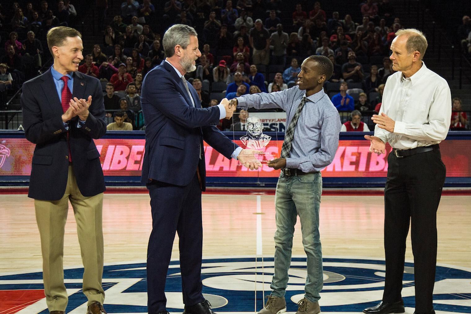 Sam Chelanga receives his plaque from Liberty University President Jerry Falwell beside Director of Athletics Ian McCaw (left) and Head Coach Brant Tolsma during Sunday's ceremony in the Vines Center, where the Athletics Hall of Fame is housed. (Photo by Leah Seavers) 