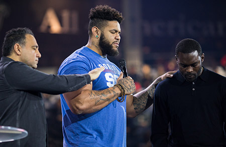 Liberty Senior Resident Shepherd Nick Acree prays over Michael Vick with Senior Vice President for Spiritual Development David Nasser (left). (Photo by Leah Seavers)