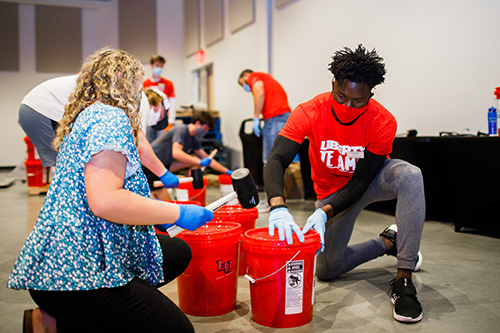 Students pack buckets of cleaning supplies to support hurricane relief efforts in the Gulf