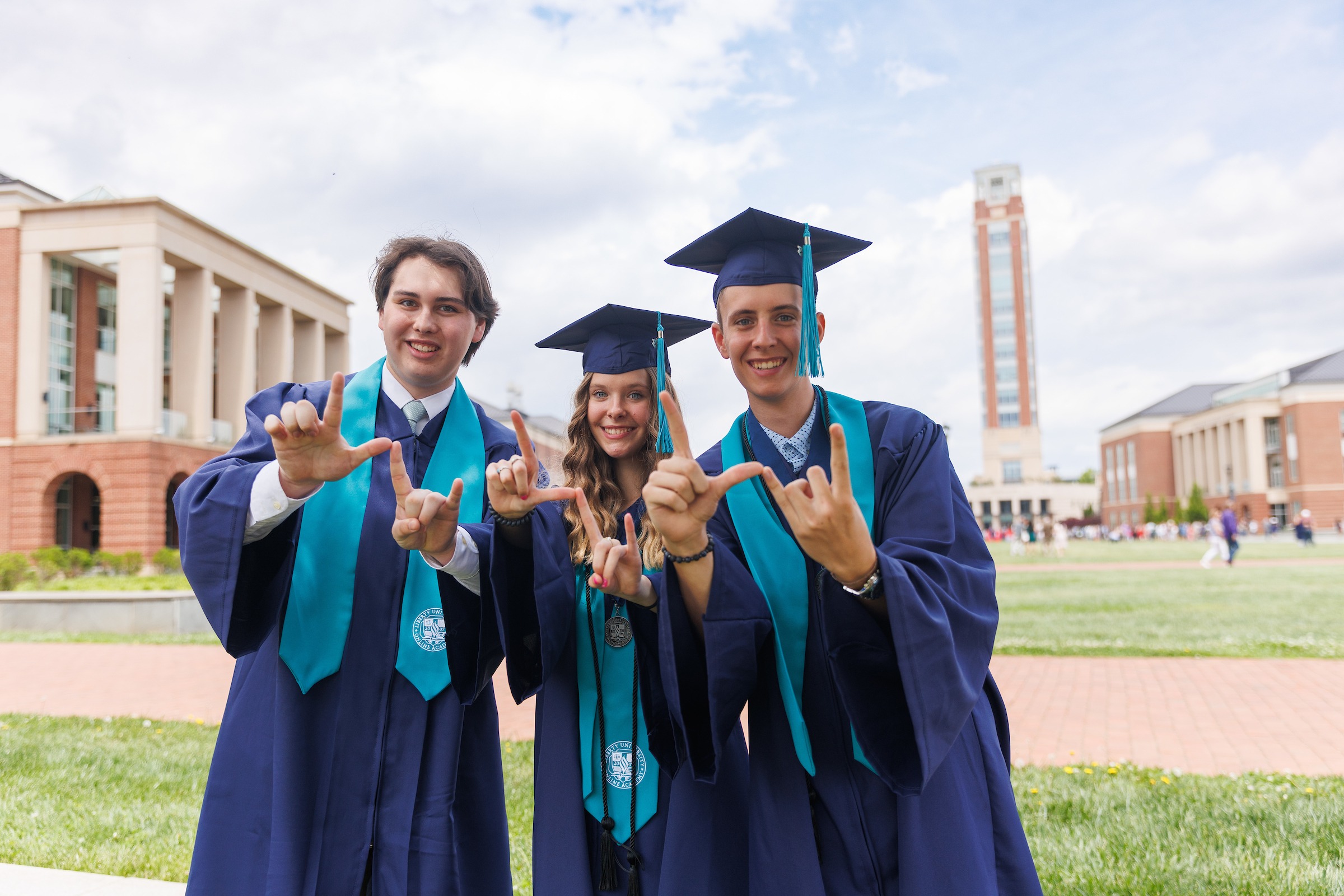 Three LUOA graduates signaling LU with their hands