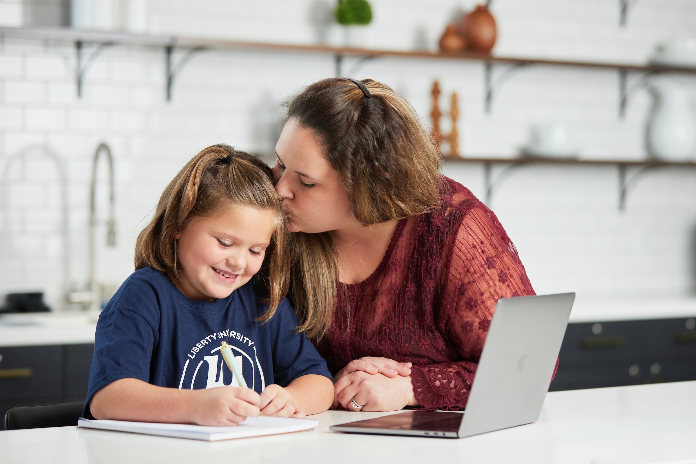 Mother kissing her LUOA student daughter on the forehead