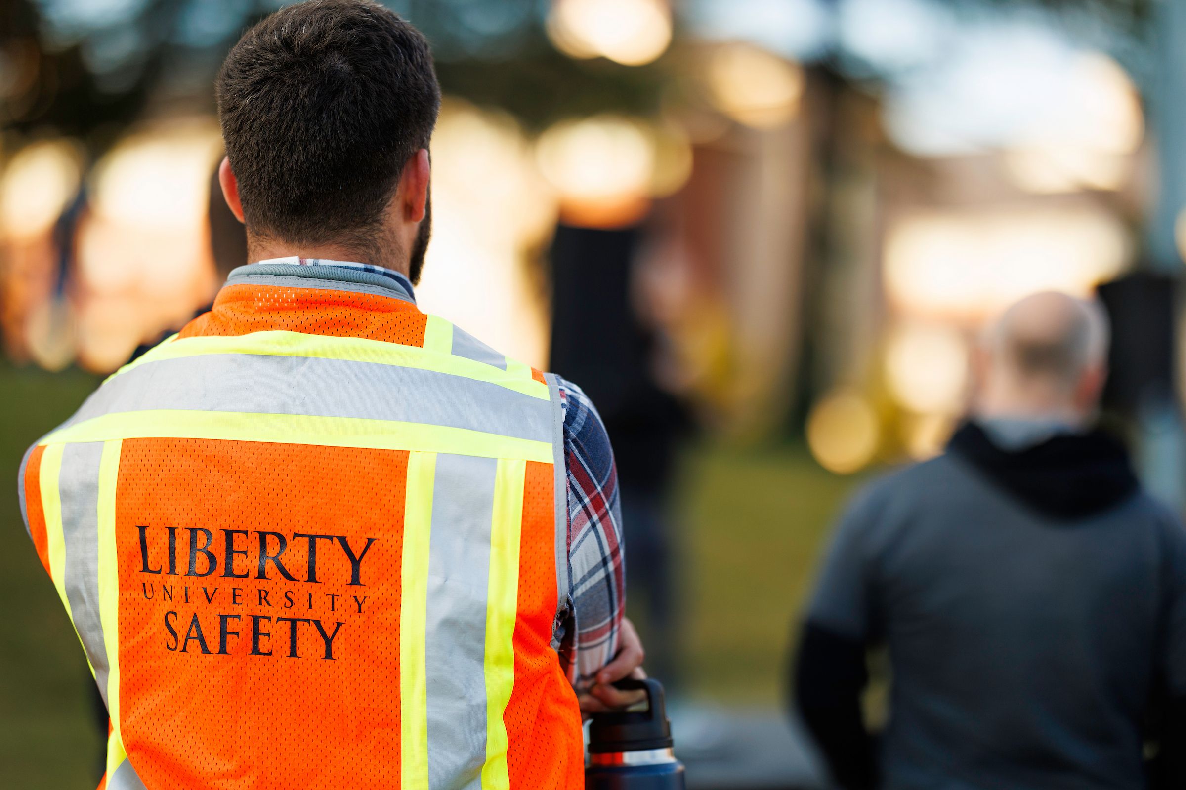 Man wearing a fluorescent orange vest that says Liberty University Safety