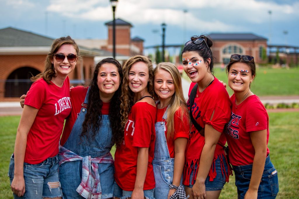 Friends celebrating game day in red Liberty Flames t-shirts